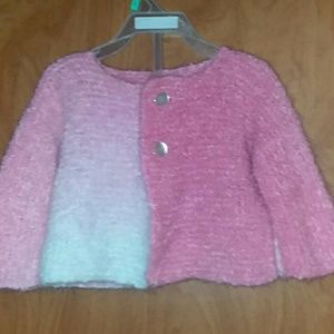 An infants handmade sweater in pink ombre.